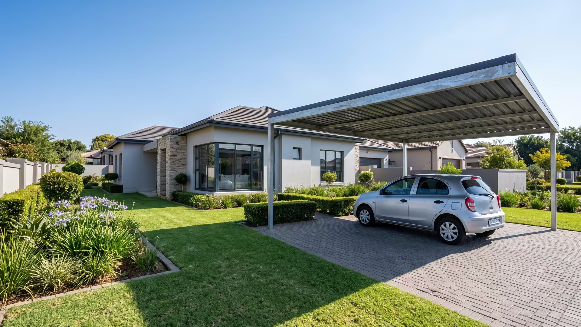 Single steel carport with a charcoal IBR roof covering one car beside a suburban Johannesburg home